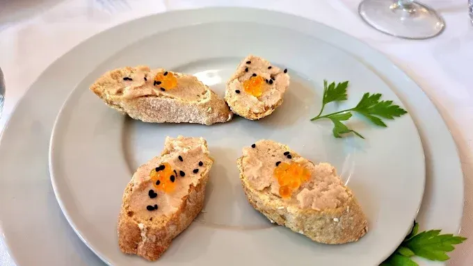 Un plato blanco cubierto con tres rebanadas de pan y un trozo de comida.