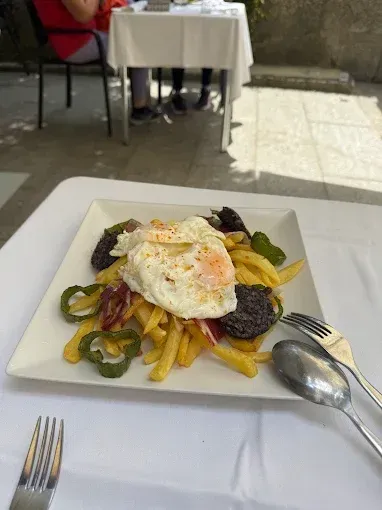Un plato de comida con un huevo frito encima de papas fritas sobre una mesa.