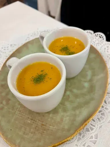 Dos tazas de sopa en un plato sobre una mesa.