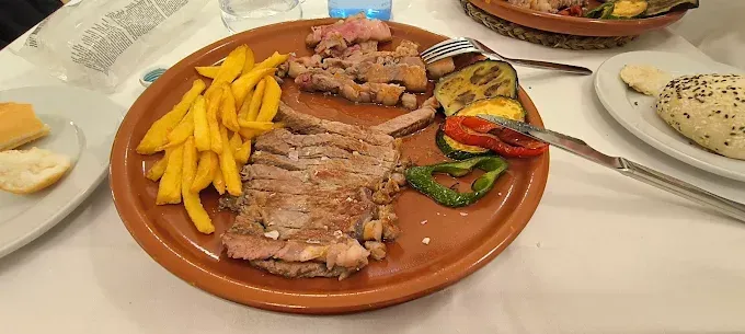 Un plato de comida con patatas fritas y verduras en una mesa.