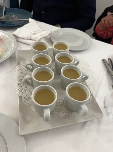 Una bandeja con pequeñas tazas de sopa sobre una mesa.