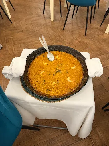 Una sartén de arroz con camarones y una cuchara sobre una mesa.