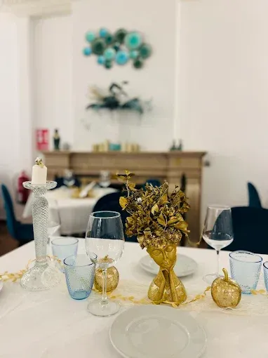 Una mesa con platos, vasos, velas y un jarrón con flores encima.