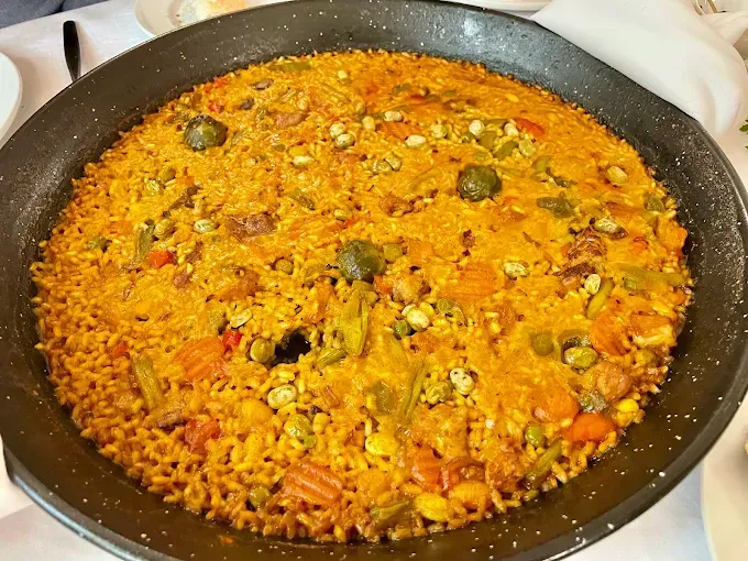 Una sartén llena de arroz y verduras sobre una mesa.