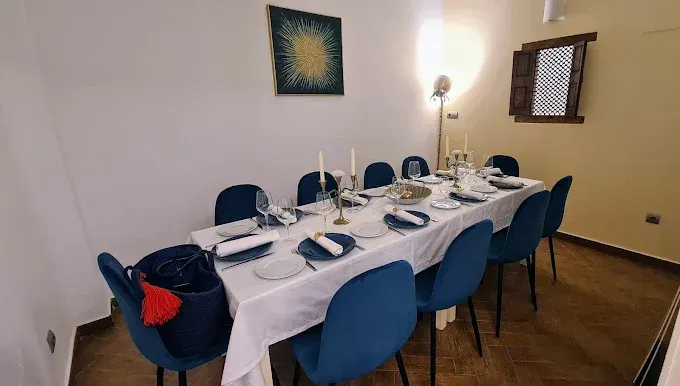 Una mesa de comedor larga con sillas azules y un mantel blanco.