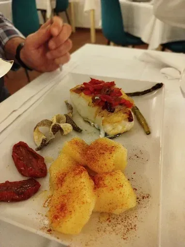 Un plato de comida con patatas y carne en una mesa.