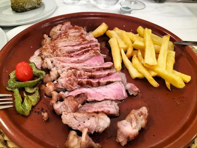 Un plato de carne y patatas fritas en una mesa