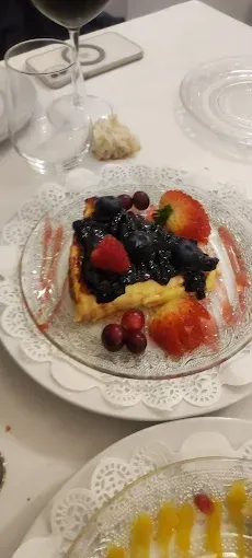 Un plato de comida con bayas y una copa de vino en una mesa.