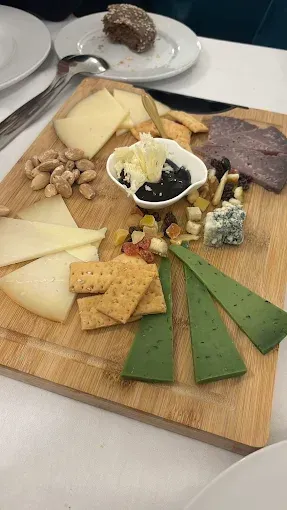 Una tabla de cortar de madera cubierta con una variedad de quesos y galletas.