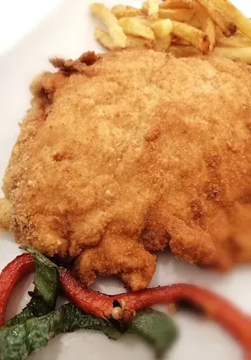 Un plato blanco cubierto con pollo frito y papas fritas.