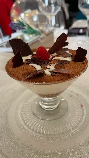 Un primer plano de un postre en un vaso sobre un plato sobre una mesa.