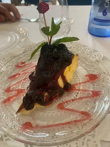 Una rebanada de tarta de queso con salsa de arándanos en un plato de vidrio.