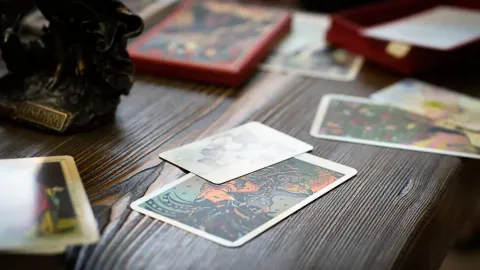 Cartas del tarot sobre una superficie de madera, con una estatua y una caja.