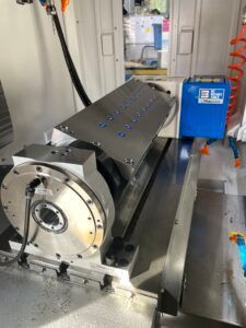 Eine CNC-Maschine mit Drehtisch und Winkelplatte, wahrscheinlich zum Fräsen von Metallteilen.