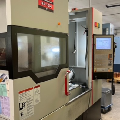 Eine grau-schwarze CNC-Fräsmaschine mit geöffnetem Bedienfeld und Sicherheitstür.