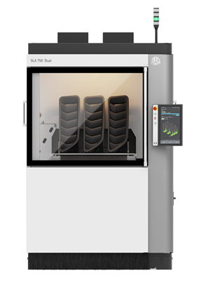 Großer industrieller 3D-Drucker mit transparenter Tür, durch die drei dunkel gefärbte Objekte im Inneren sichtbar sind.