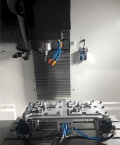 CNC-Fräsmaschine mit einem auf einer Vorrichtung montierten Metallwerkstück, Düsen sichtbar, zur Fertigung.