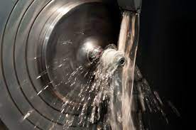 Ein rotierendes Metallteil wird in einer Maschinenwerkstatt mit einem Flüssigkeitsstrahl gekühlt.