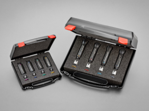 Zwei schwarze Werkzeugkoffer sind geöffnet, jeder enthält mehrere Werkzeuge in Schaumstoffeinlagen; rote Verschlüsse.