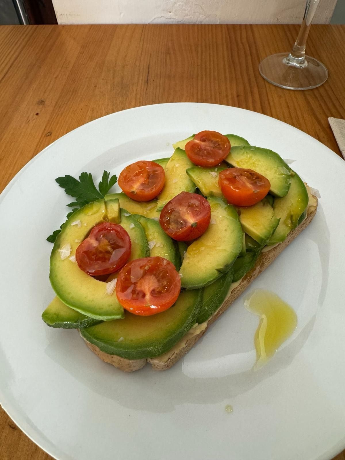 Un plato blanco cubierto con rodajas de aguacate y tomates.