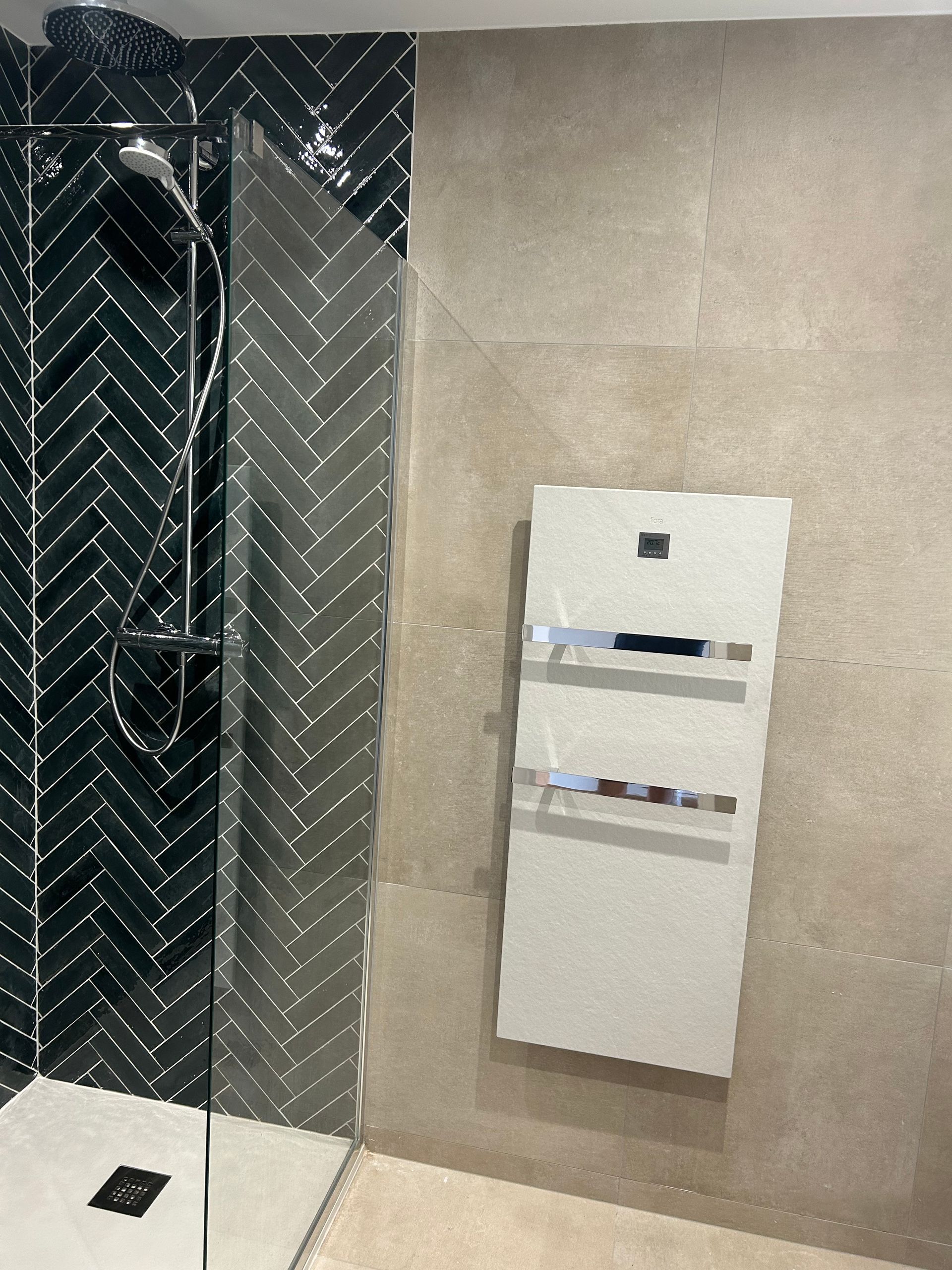 Mur de salle de bains avec un distributeur mural blanc à côté d’une cabine de douche en tôle à damier noire.