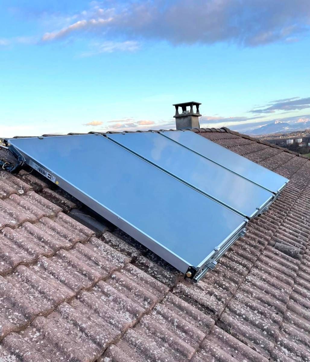 Trois panneaux solaires installés sur un toit, une cheminée est visible derrière les panneaux