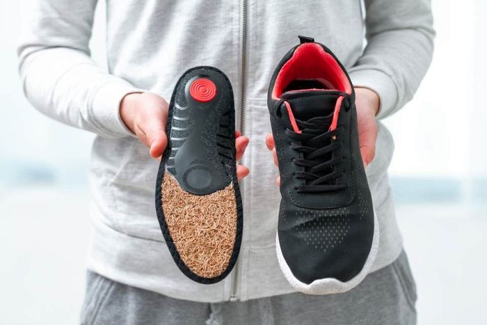 Eine Person hält ein Paar Schuhe in den Händen.