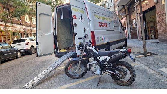 Una motocicleta está estacionada al costado de la carretera al lado de una camioneta.