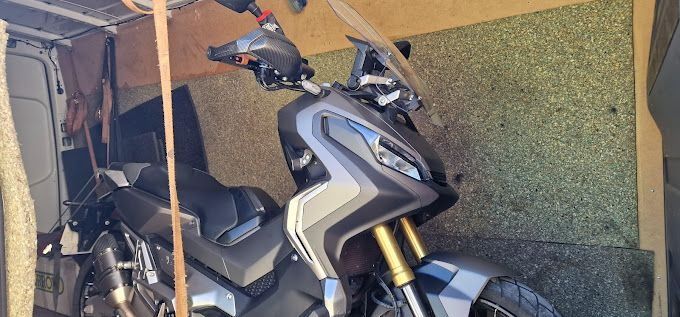Una motocicleta está estacionada en un garaje al lado de una pared.