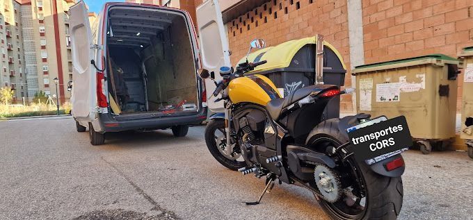Una motocicleta amarilla está estacionada delante de una camioneta.