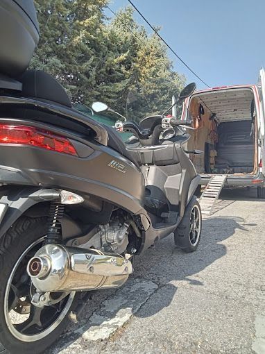 Un scooter está estacionado al costado de la carretera al lado de una camioneta.