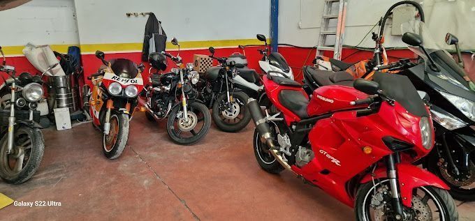 Un montón de motocicletas están estacionadas en un garaje.