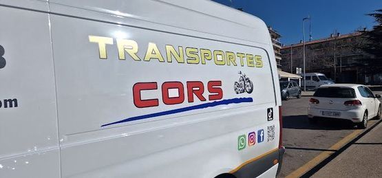 Una camioneta blanca con la palabra cors está estacionada en un estacionamiento.