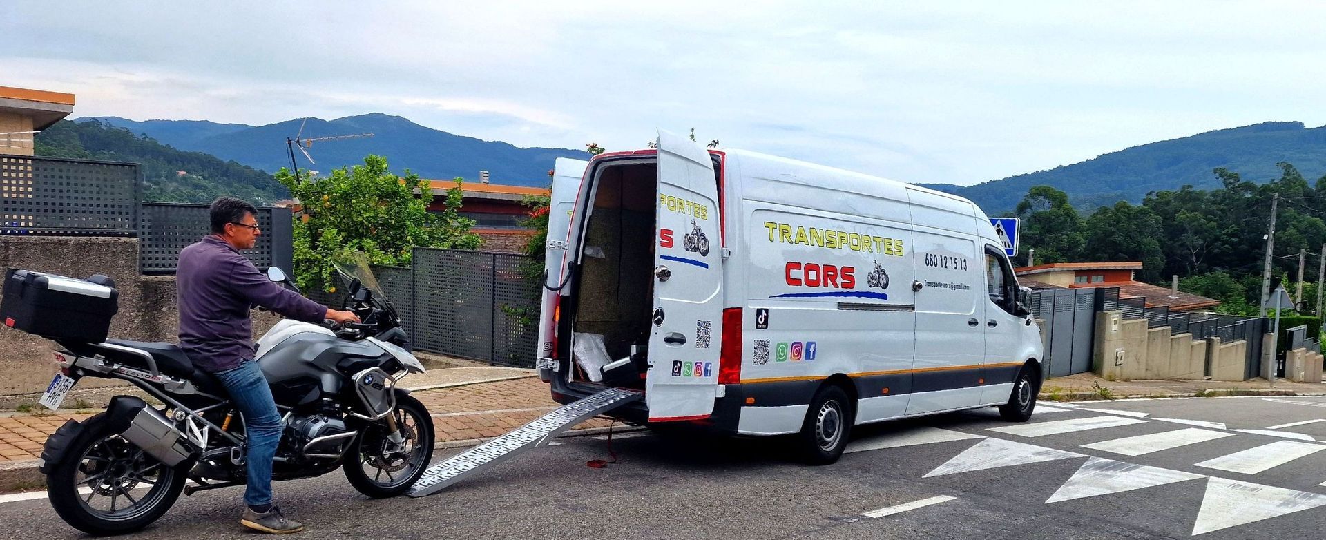 Un hombre viaja en motocicleta al lado de una camioneta blanca.