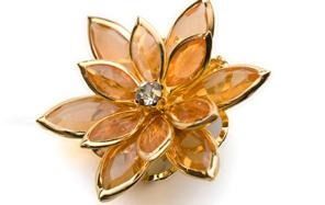 Broche floral de oro con pétalos de ámbar y una gema central transparente.