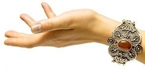 Mano con una pulsera de oro ornamentada y una piedra de ámbar, con la palma hacia arriba.
