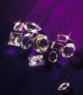 Varias piedras preciosas transparentes sobre un fondo púrpura con reflejos brillantes.