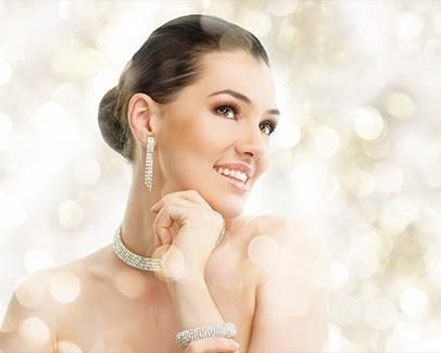 Mujer sonriente con elegantes joyas y un suave fondo bokeh.
