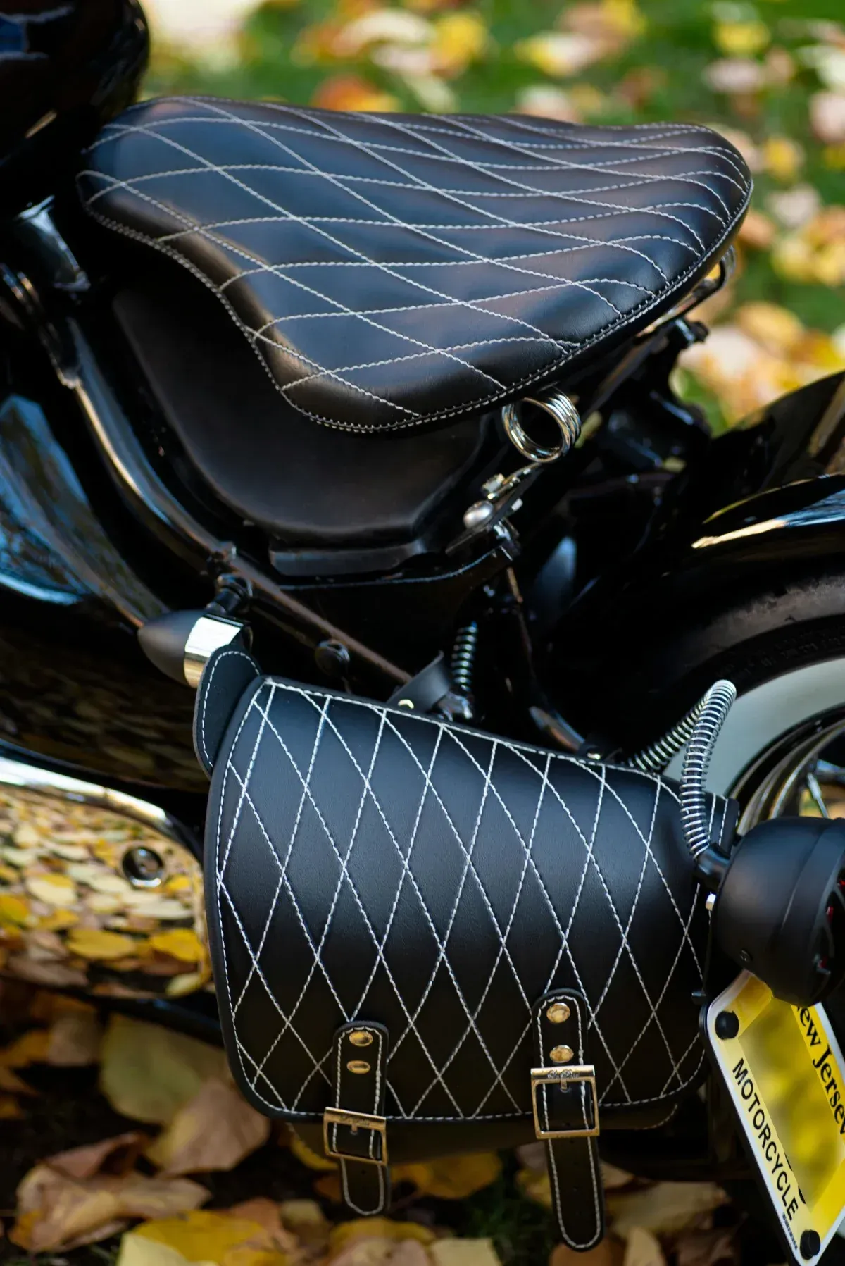 Asiento y alforja de motocicleta de color negro con costuras de diamante y herrajes plateados.