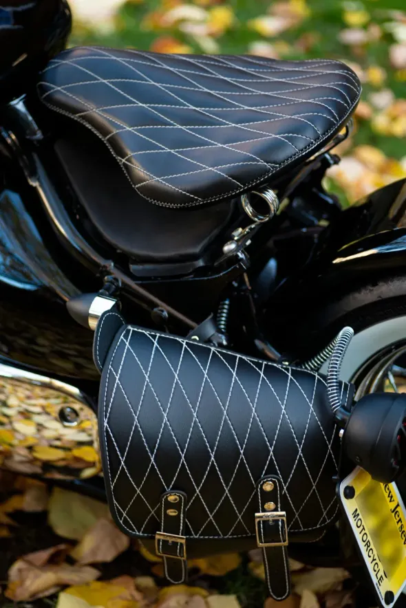 Asiento y alforja de motocicleta de color negro con costuras de diamante y herrajes plateados.