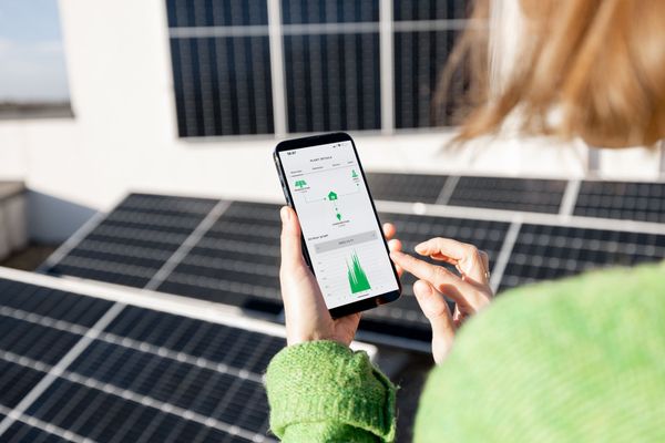 Une femme vérifie la performance de ses panneaux solaires sur son téléphone