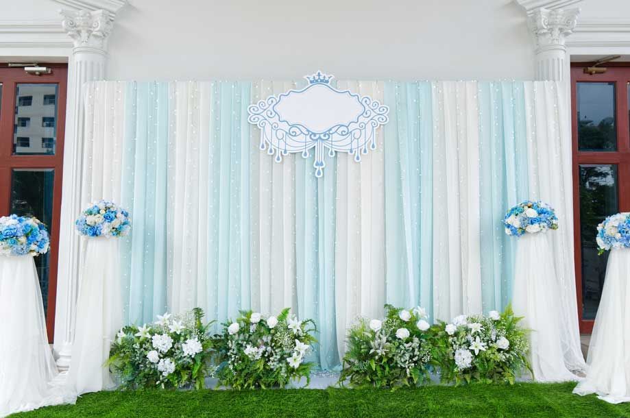 Un telón de fondo de boda con cortinas y flores azules y blancas.