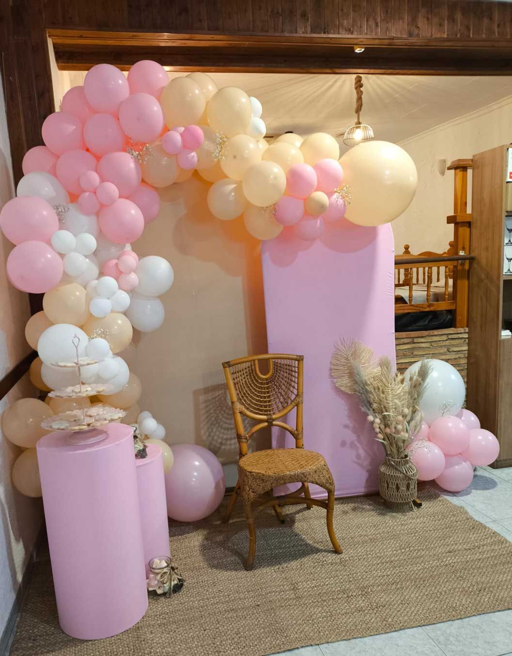 Una habitación decorada con globos rosas y blancos y una silla.