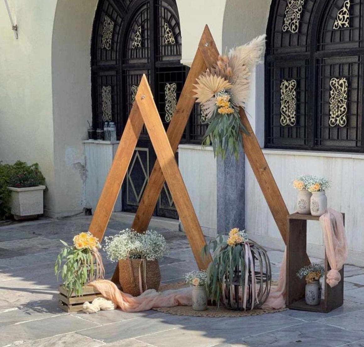 Un arco de madera con flores está delante de un edificio.