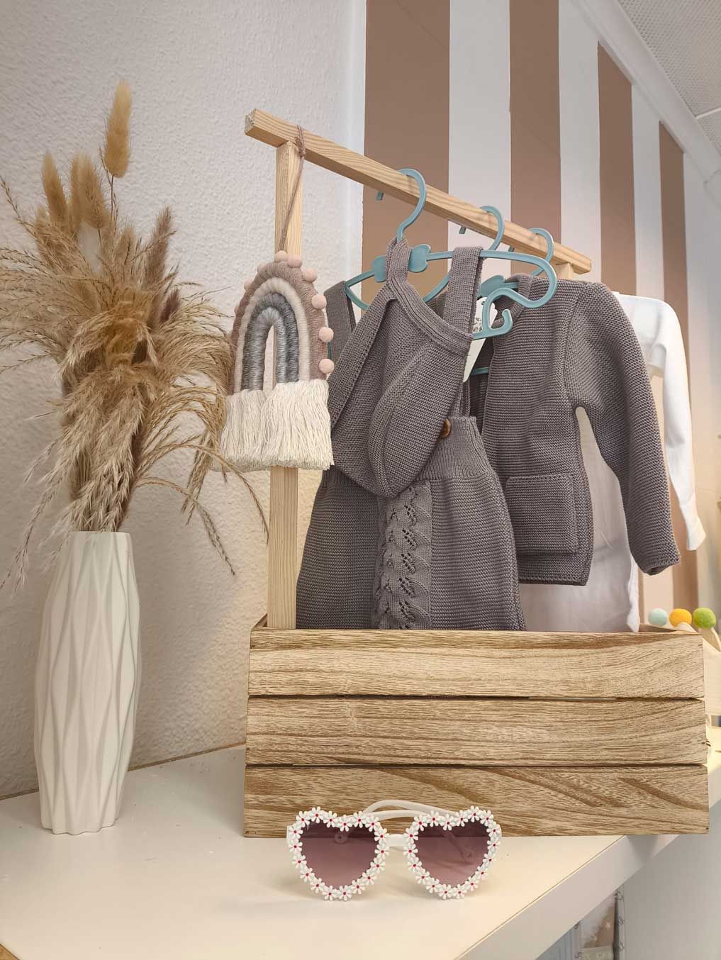 Una caja de madera llena de ropa y gafas de sol sobre una mesa.