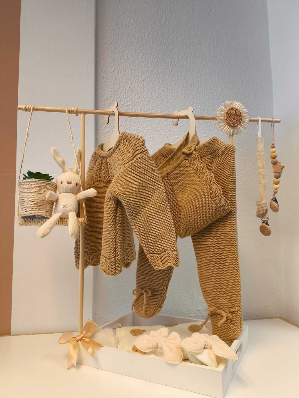 La ropa de un bebé está colgada en un perchero sobre una mesa.