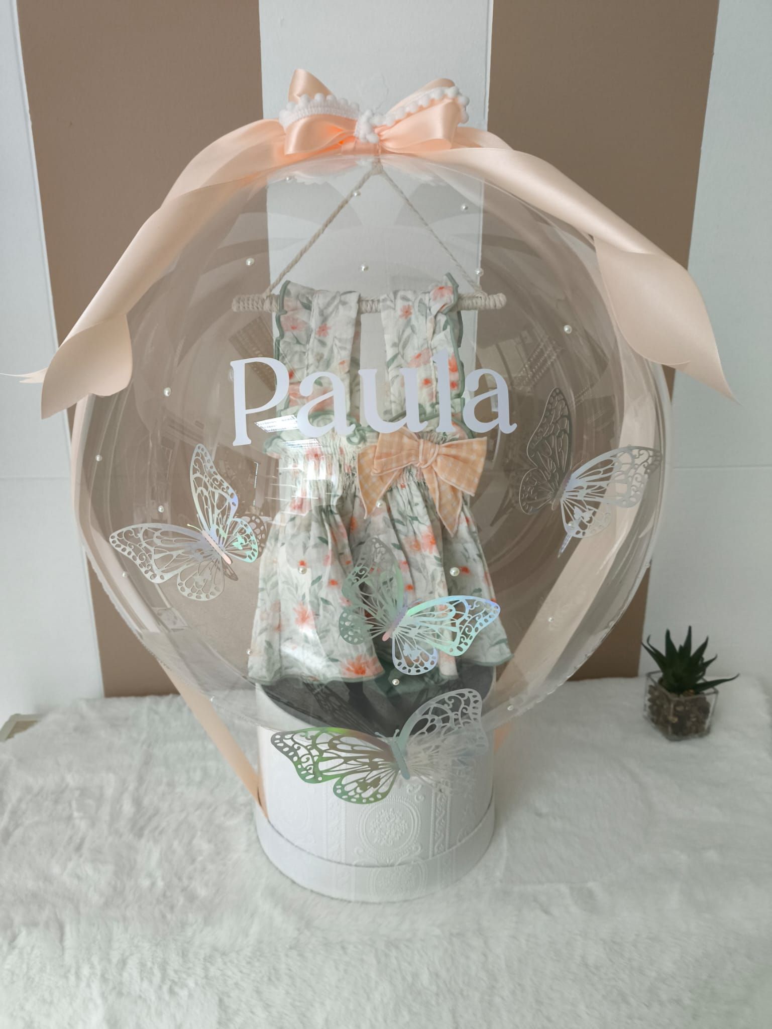 Un globo transparente con el nombre Paula está sobre una mesa.