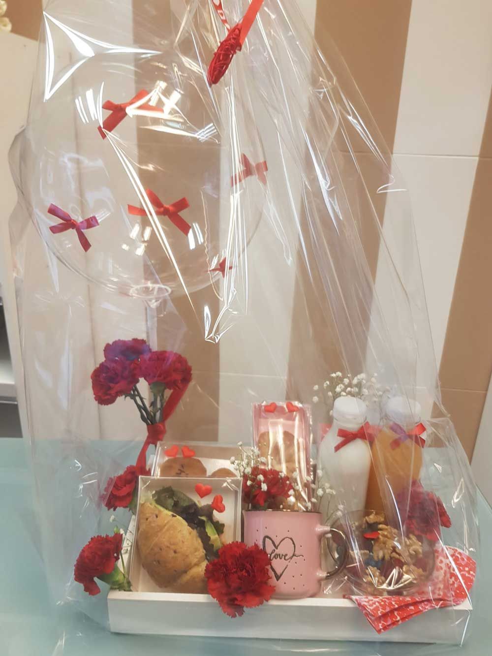 Una bandeja llena de comida y flores está envuelta en plástico.