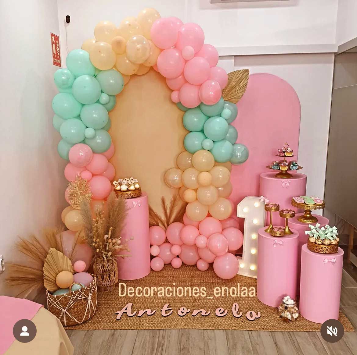 Una habitación decorada con globos rosas y verdes y un número 1