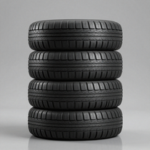 Cuatro neumáticos de coche negros apilados verticalmente sobre un fondo gris.